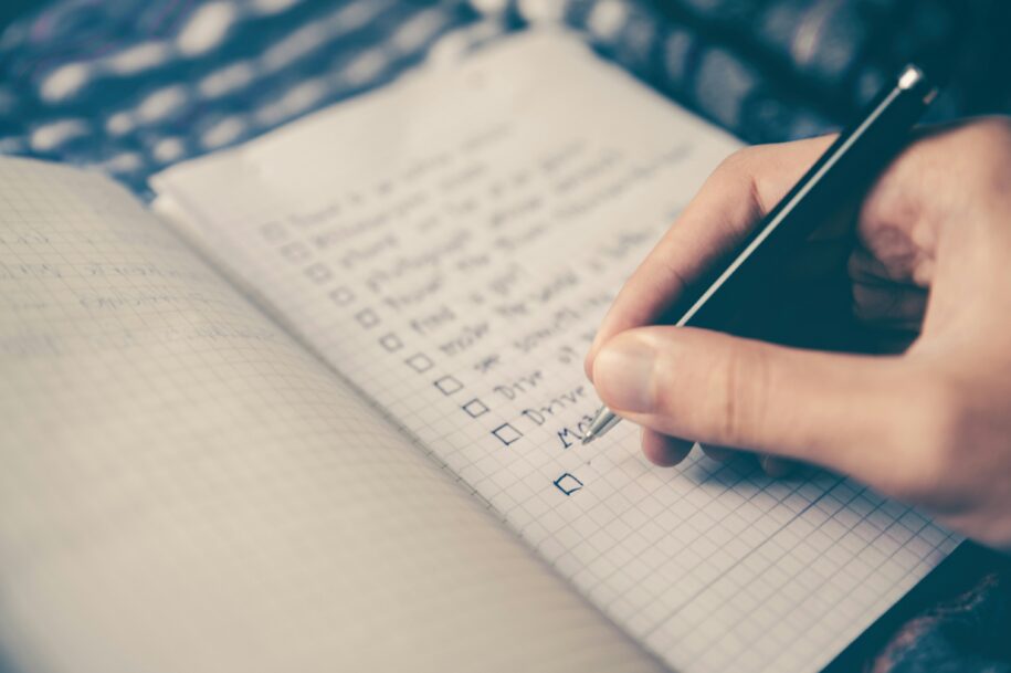 a hand writing a checklist with customer onboarding best practices
